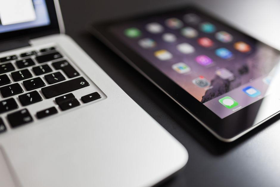 Close-up de um laptop e tablet em uma mesa preta, mostrando os essenciais da tecnologia moderna.