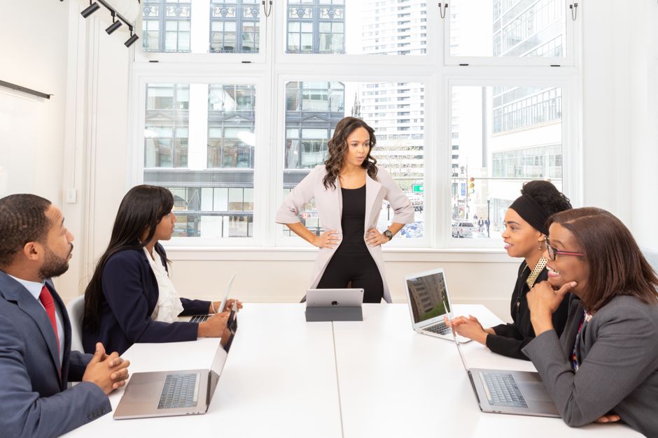 Um grupo diversificado de profissionais engajados em uma reunião em um escritório moderno com laptops e vista para a cidade.