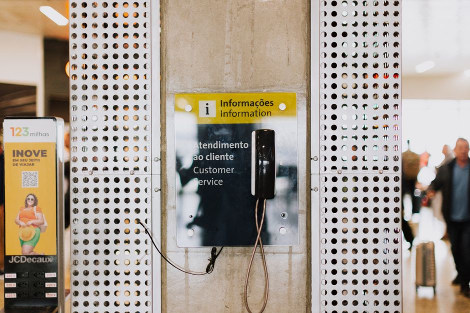 Telefone público para atendimento ao cliente em uma movimentada entrada de estação com sinalização.