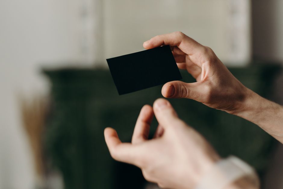 Foto em close-up de mãos segurando um cartão preto em branco, perfeito para mockup ou propósitos de template.