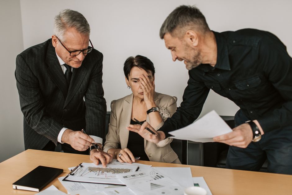 Equipe de negócios em uma reunião tensa analisando gráficos e relatórios em uma mesa de escritório.