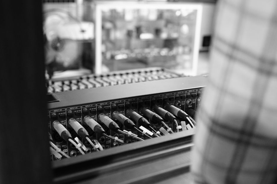 Vista aproximada de equipamentos de áudio com cabos patch em preto e branco, destacando tecnologia e conexão.