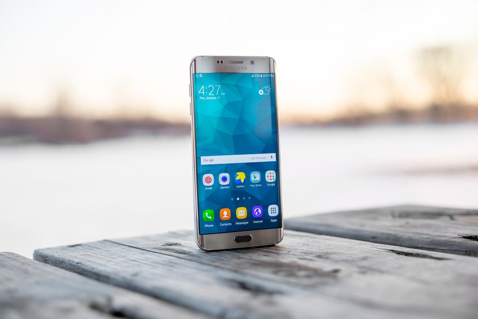 Smartphone Samsung colocado sobre uma superfície de madeira ao ar livre durante o pôr do sol.